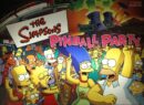 A group of simpsons characters in front of the simpsons pinball machine.