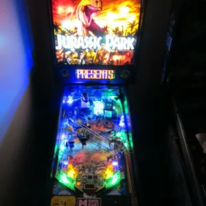 A lighted pinball machine in the dark.