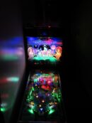 A pinball machine with lights and a video game screen.