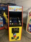A pac-man arcade machine sitting in the middle of a room.