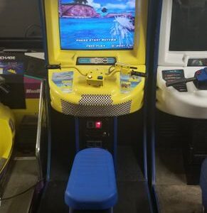 A yellow arcade machine with a blue stool in front of it.