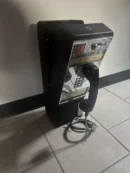 A black and white photo of an old payphone.