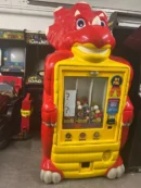 A large red and yellow claw machine with many small prizes.