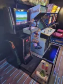 A room with several arcade machines and a large tv.